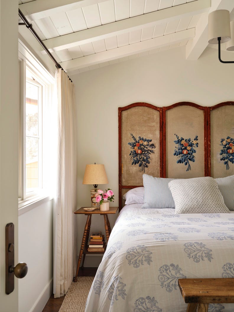 a bedroom with an antique screen as a headboard