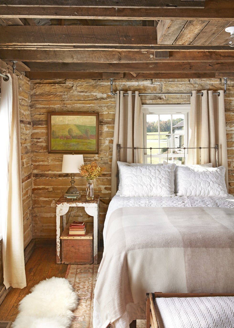 a rustic bedroom with exposed stone walls and neutral bedding