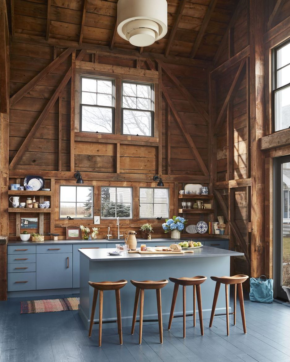 rustic kitchen with blue painted floor and blue cabinets paired with natural wood walls, ceiling, and barstools