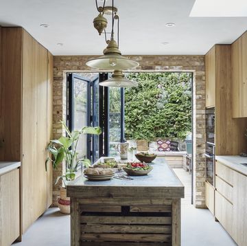 a kitchen with wooden cabinets, concrete worktops and a freestanding zinc topped island