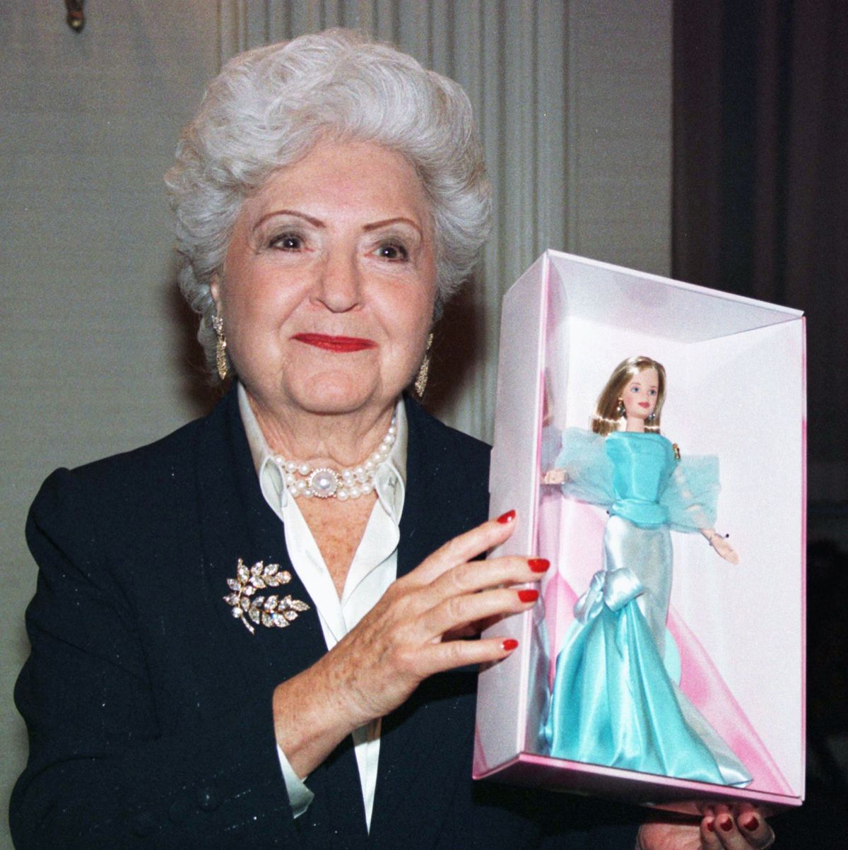 barbie creator ruth handler holding a doll inside a box and smiling for a photo
