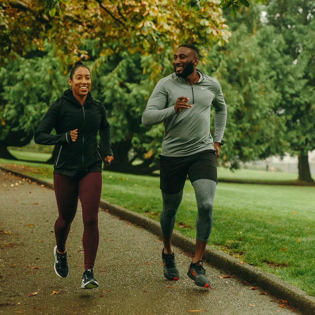 two runners on a paved path through a park