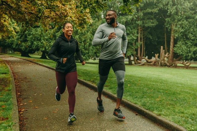 two runners in athletic gear jogging on a park path