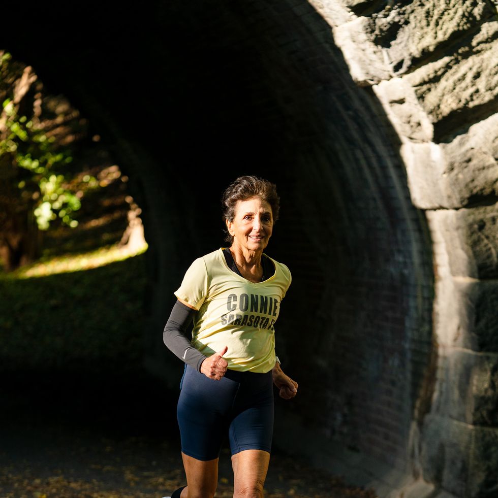 an older woman running through a tunnel on a paved path