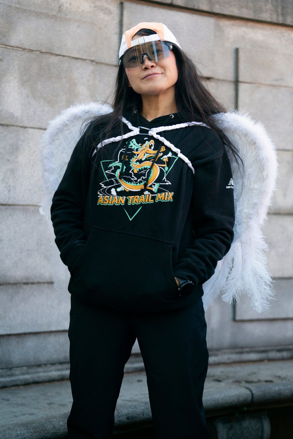 a portrait of a woman wearing angel wings and a sweatshirt reading asian trail mix