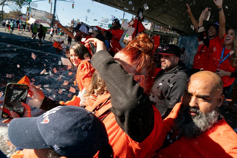 a group of people wearing matching orange shirts cheer on runners during a marathon