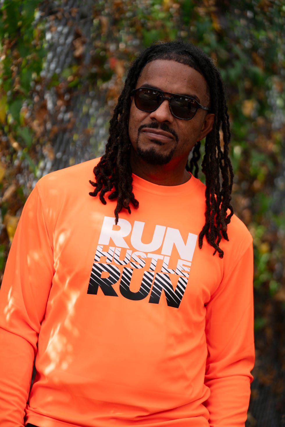 a portrait of a man wearing an orange shirt and sunglasses