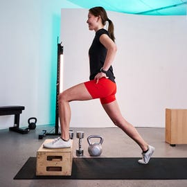 individual performing a lunge on a plyometric box in a gym setting individual performing a lunge on a plyometric box in a gym setting