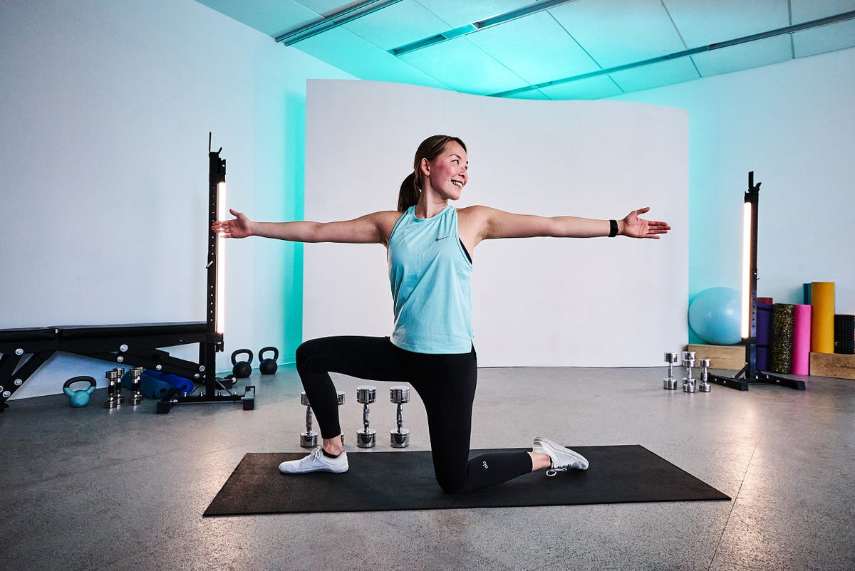 woman kneeling on yoga mat with arms outstretched