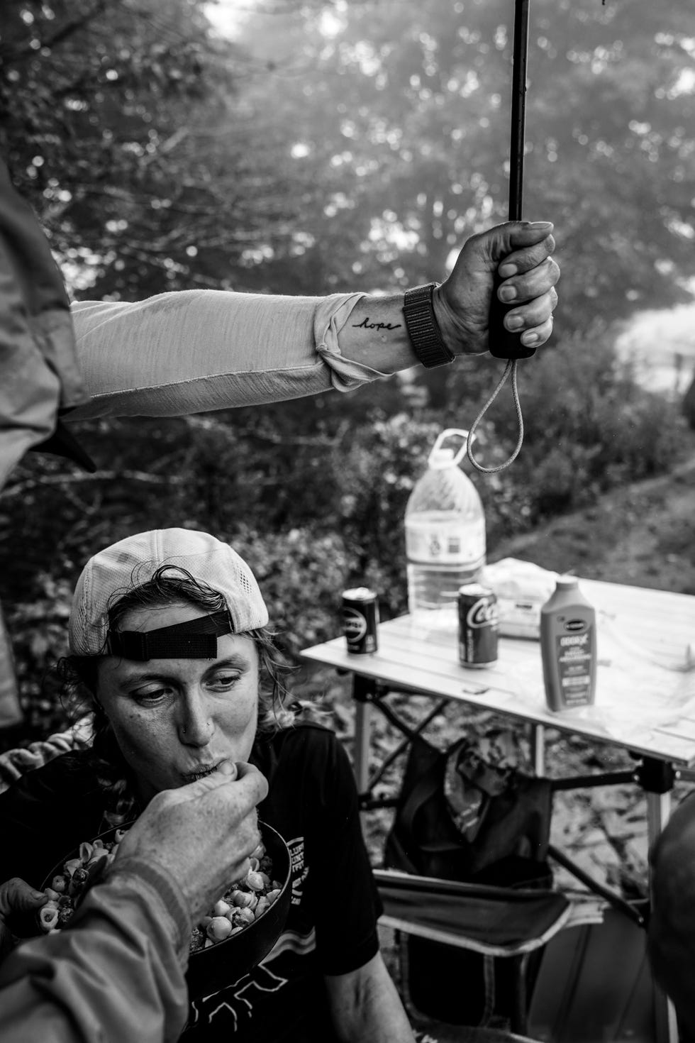 a person gives a runner a drink while holding an umbrella