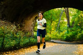 an older woman running through a tunnel on a paved path