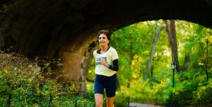 an older woman running through a tunnel on a paved path