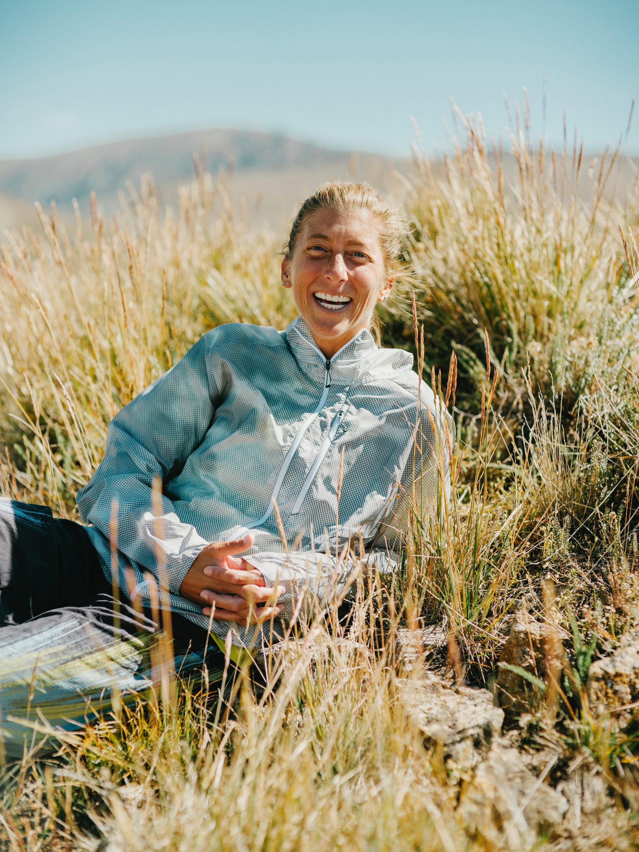 a person wearing running clothes lays in a field posing for a portrait