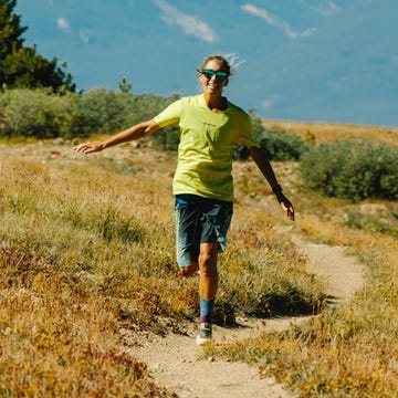 Individual running along a winding dirt path in a grassy area with trees in the background Individual running along a winding dirt path in a grassy area with trees in the background