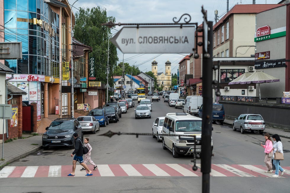 people walk across a cross walk in an urban area with cyrillic writing