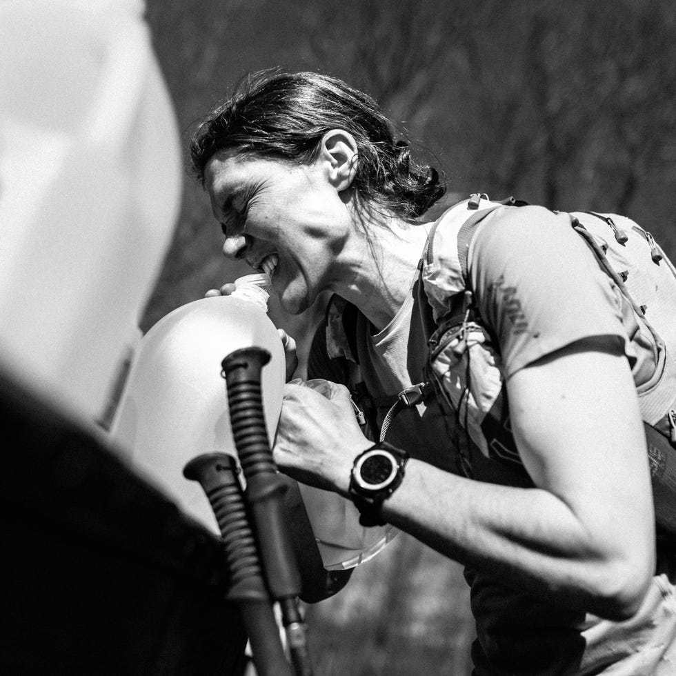 a trail runner opens a jug of water