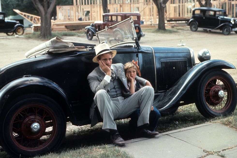 ryan o'neal and tatum o'neal in 'paper moon' sit against a car with their heads resting in their palms