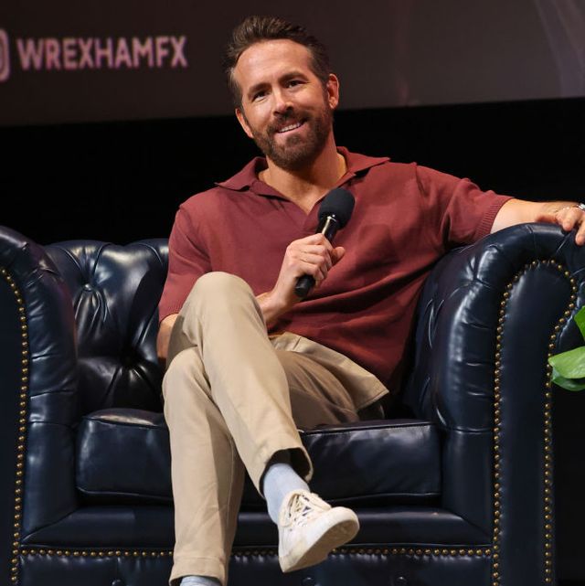 ryan reynolds sitting in a chair and smiling while holding a microphone