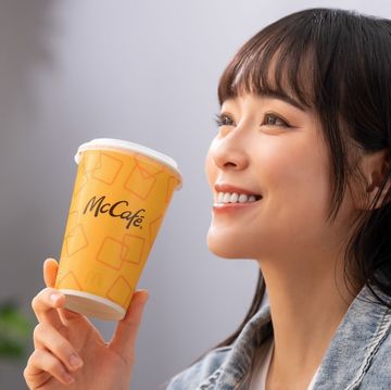 a woman holding a cup of coffee and a burger