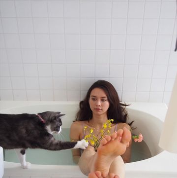a woman sitting in a bathtub with a cat on her lap