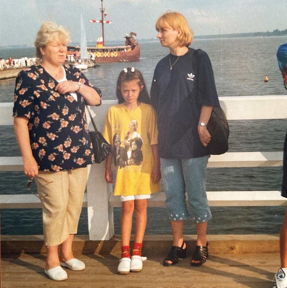 a group of people standing on a dock with a ship in the background