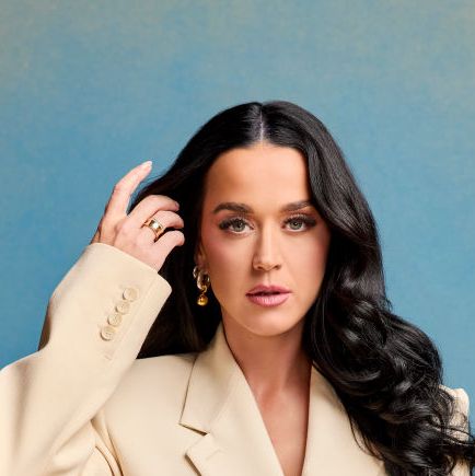 katy perry poses in a cream suit with her long hair down against a blue and yellow fade background