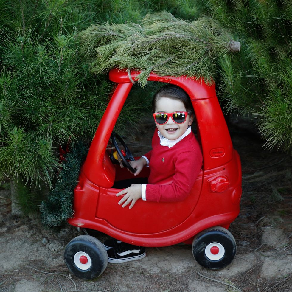 boy riding red car with christmas tree