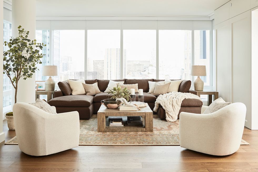 ayesha curry home tour living room with brown sofa and white armchairs