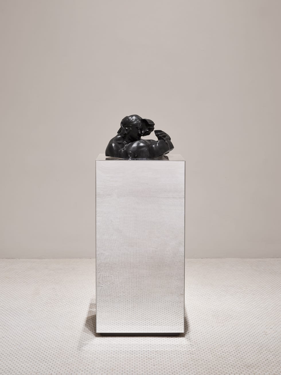 black sculpture on a reflective pedestal