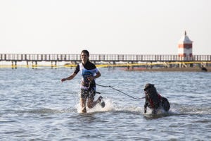 donna corre con il cane in acqua