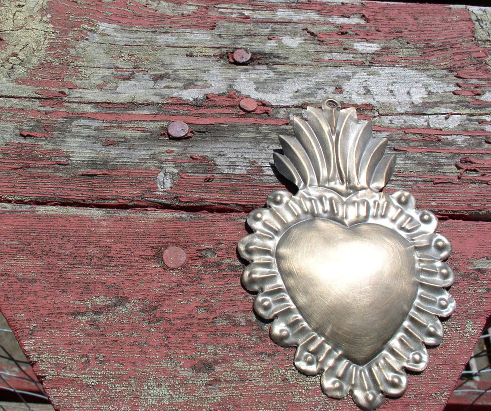 sacred heart milagro on a peeling wood background