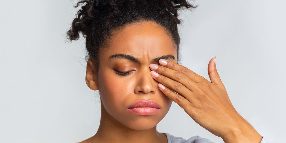 sad black girl touching her eye, suffering from conjuctivitis