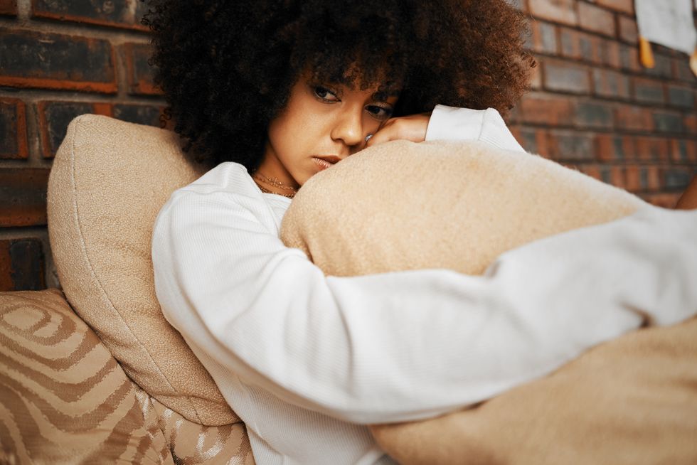 sad, depressed and lonely black woman with mental health problems hugging a pillow at home portrait of a african afro female in depression, stress and anxiety feeling unhappy living alone in a house