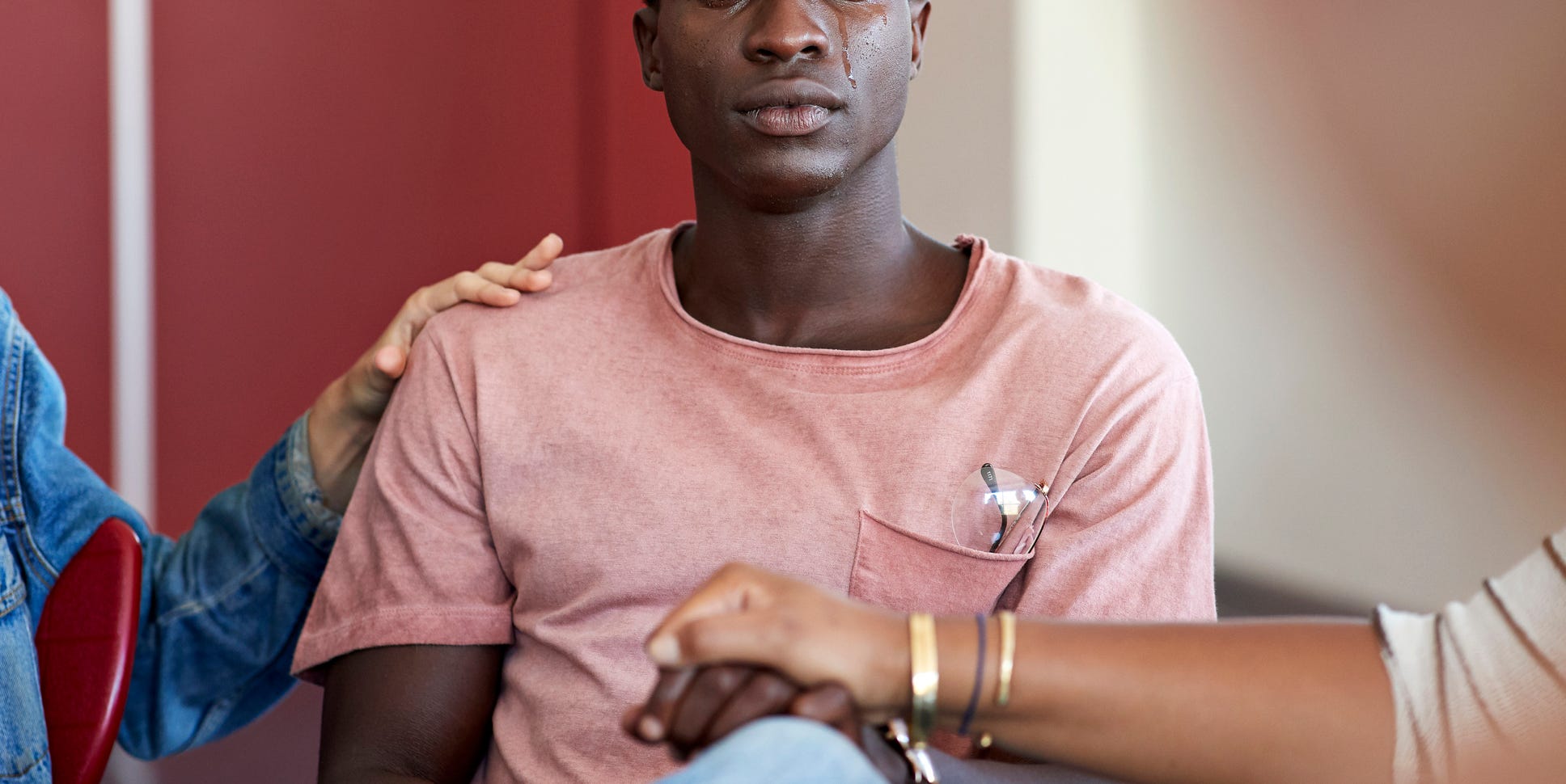 sad man being consoled by friends in group therapy