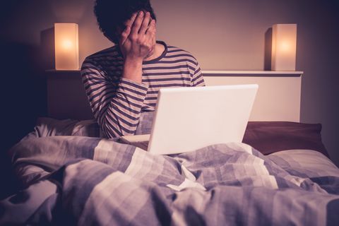 Sad man in bed with laptop
