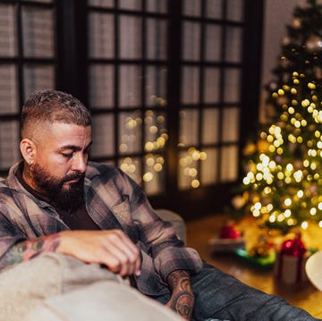 sad mature man sitting on the sofa alone on christmas day at home