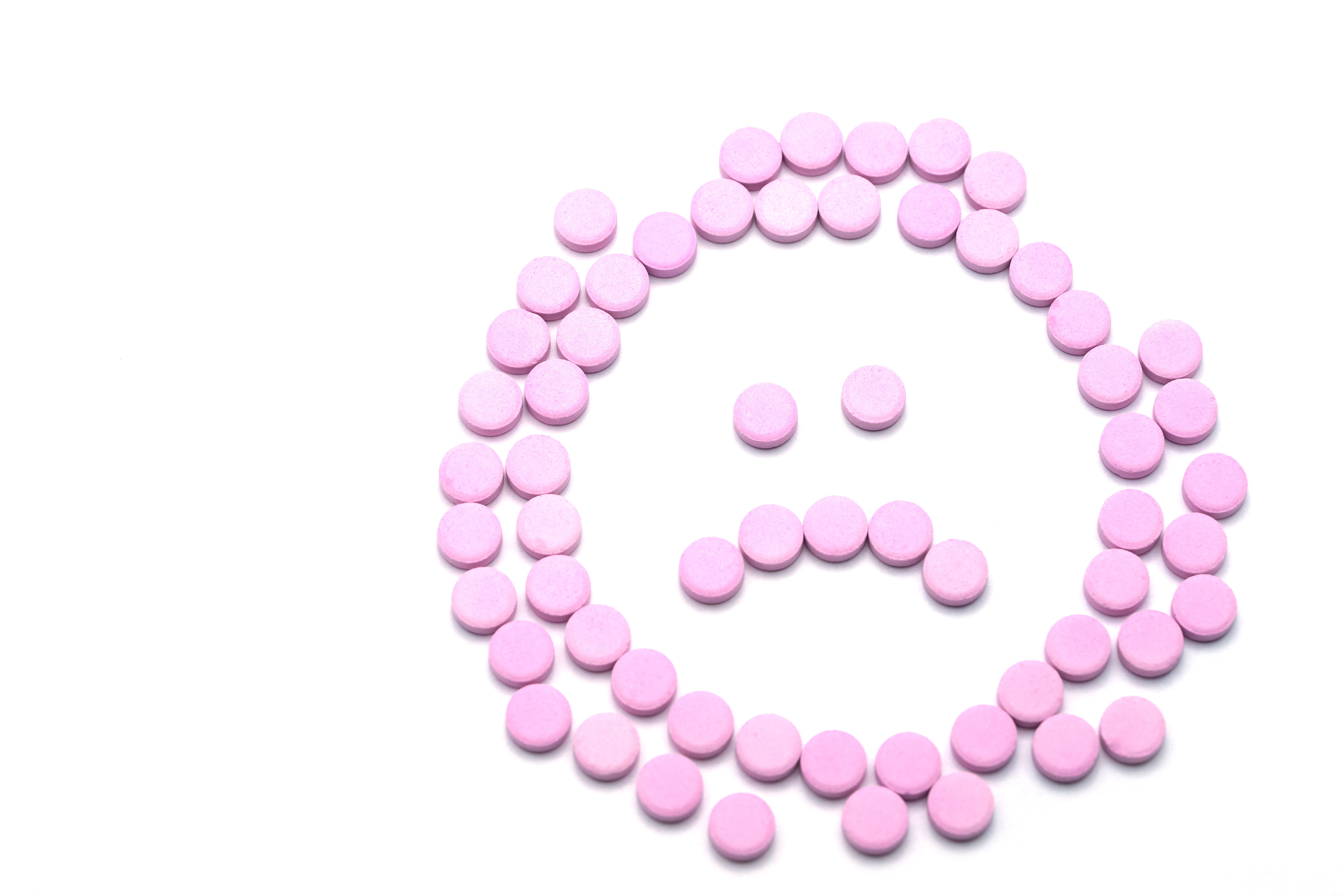 sad unhappy face of pink pills on white background tablets of drug for asthma treatment