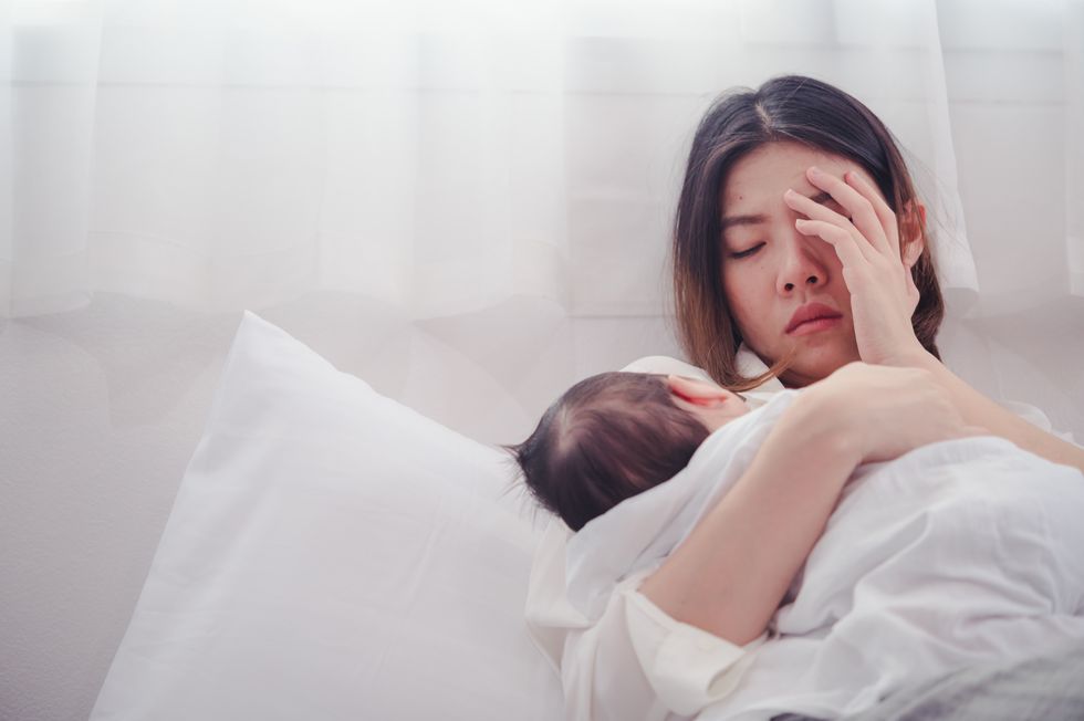 sad woman with baby lying on bed at home