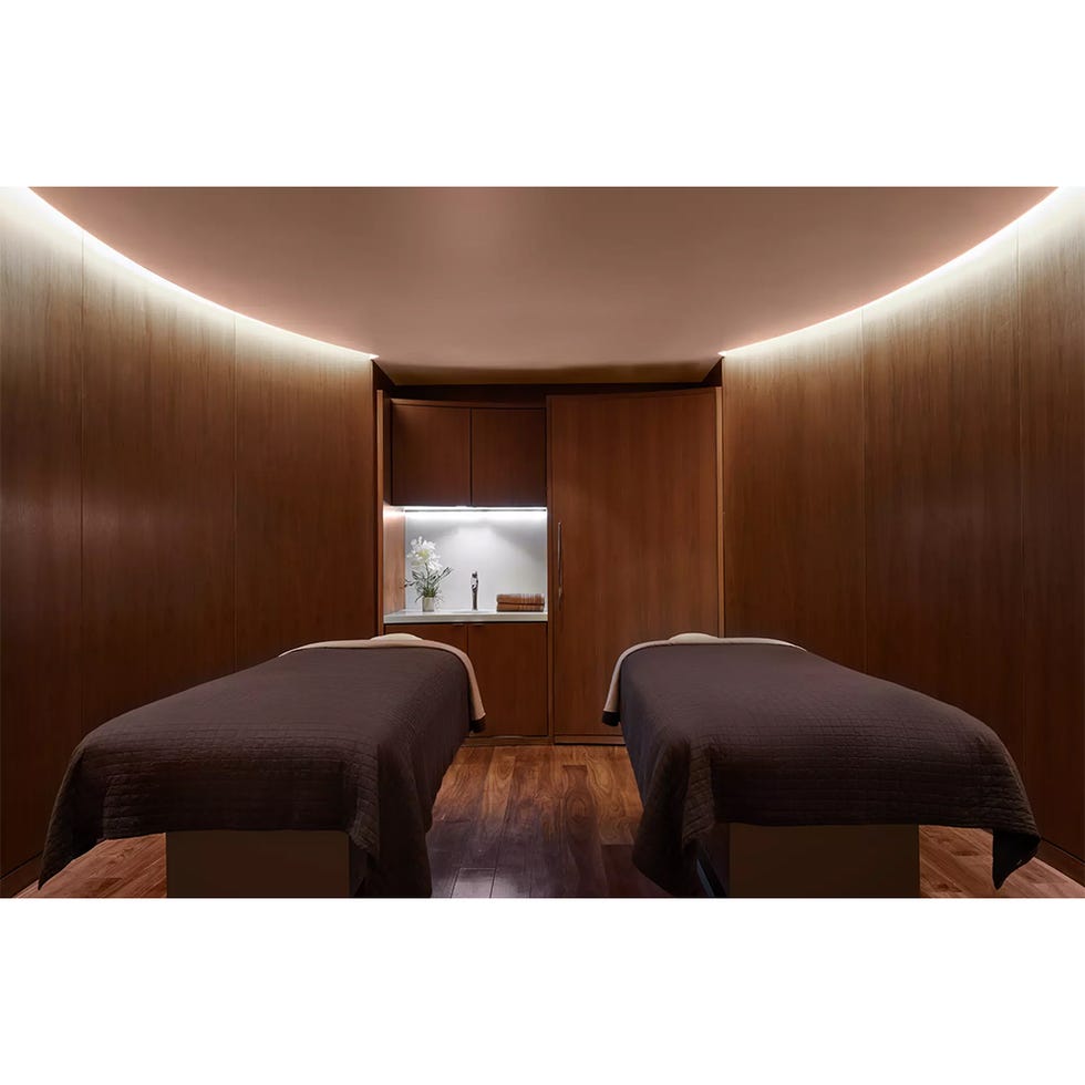 spa treatment room with two massage tables and wooden decor