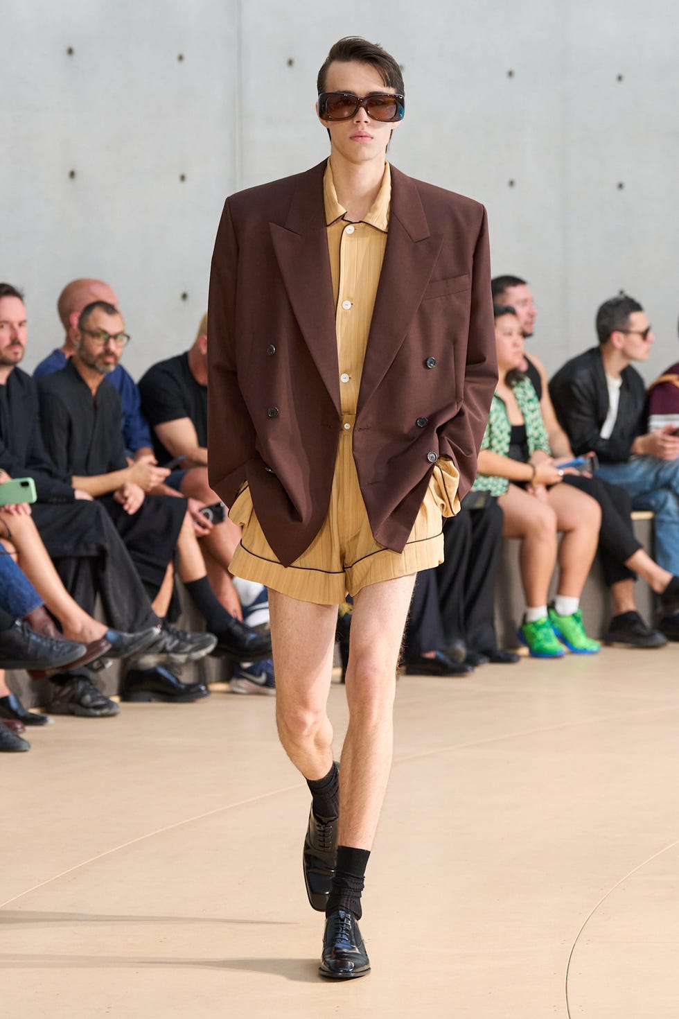 Fashionmodel präsentiert einen braunen Oversize-Blazer und beige Shorts während einer Modenschau