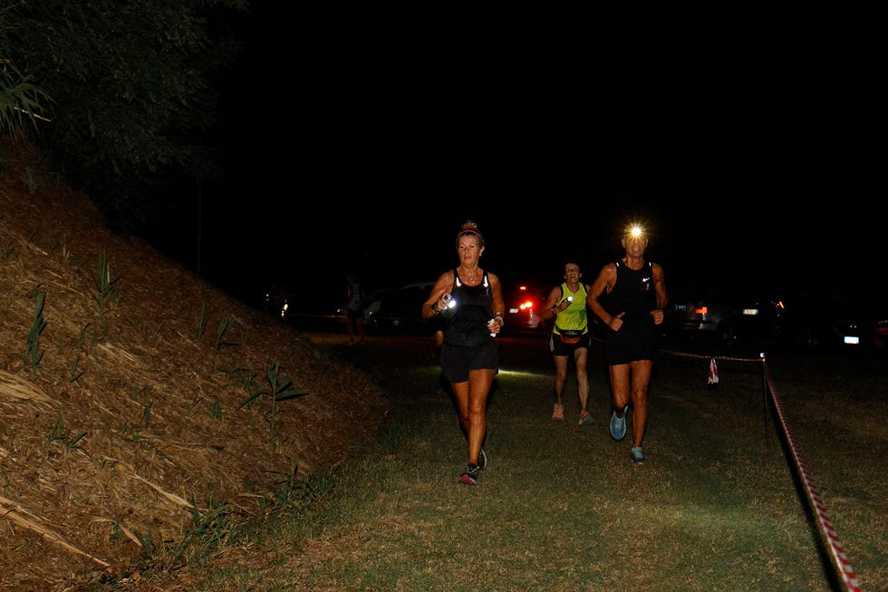 runners participating in a nighttime event illuminated by headlamps