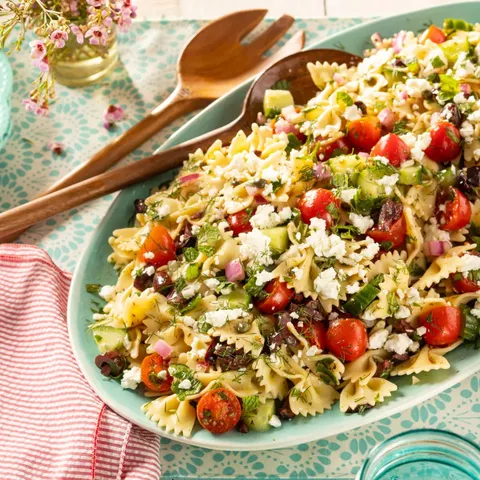 greek pasta salad with bow tie noodles and wooden spoons