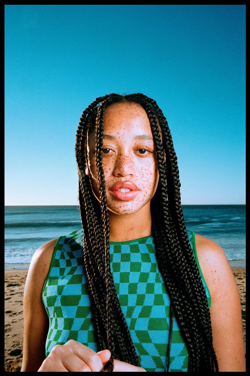 model salem mitchell stands in front of the ocean in a checkerboard tank top to illustrate her fashion resolution for 2022