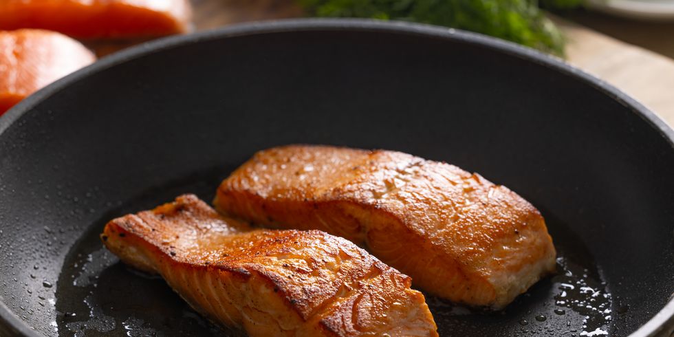 salmon fillets and herbs in an black frying pan