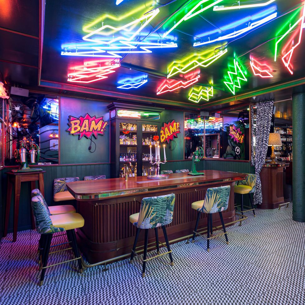 the inside of the bar featuring neon signs on the ceiling and funky carpet