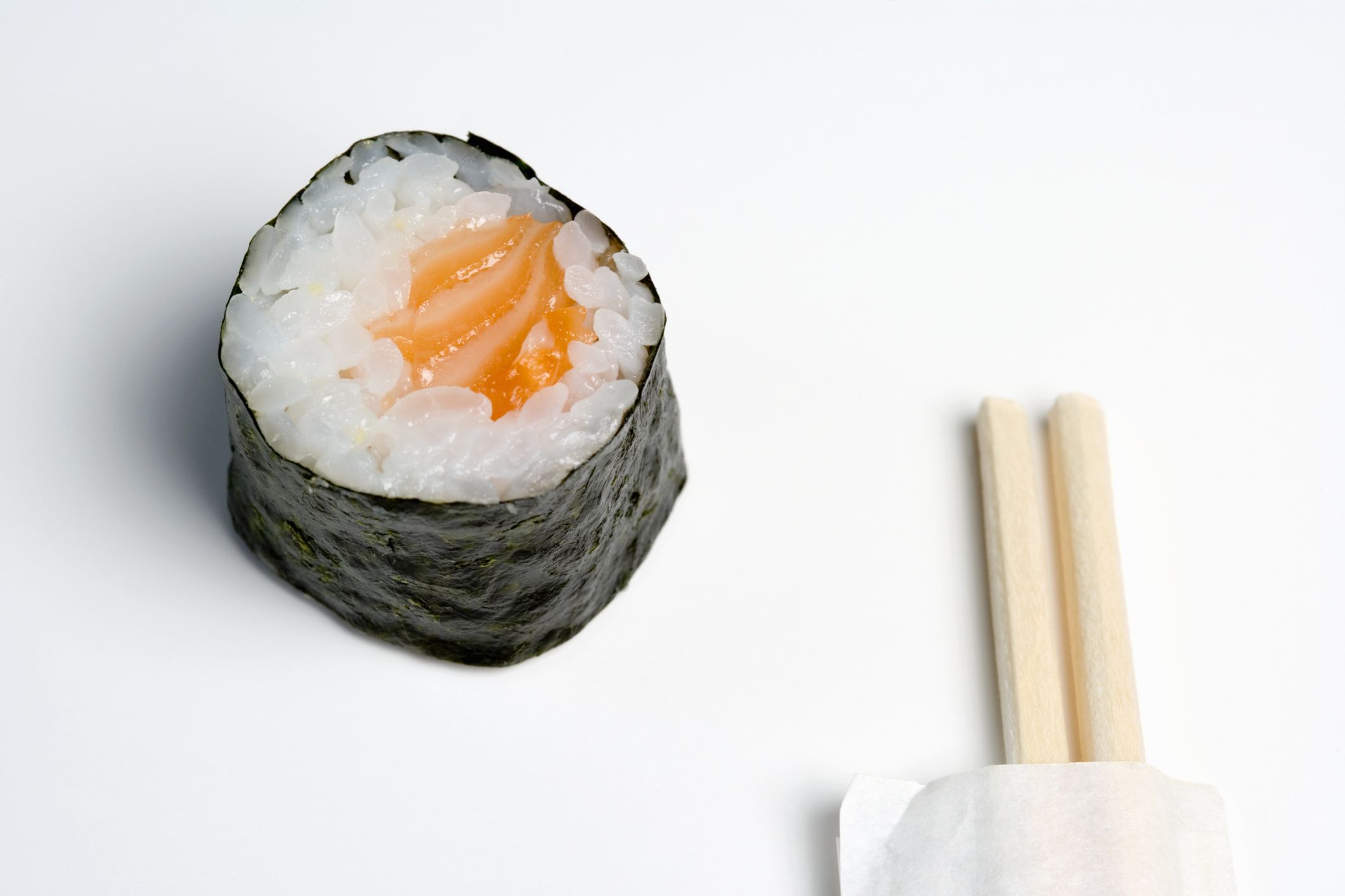 Wooden chopsticks next to salmon sushi piece