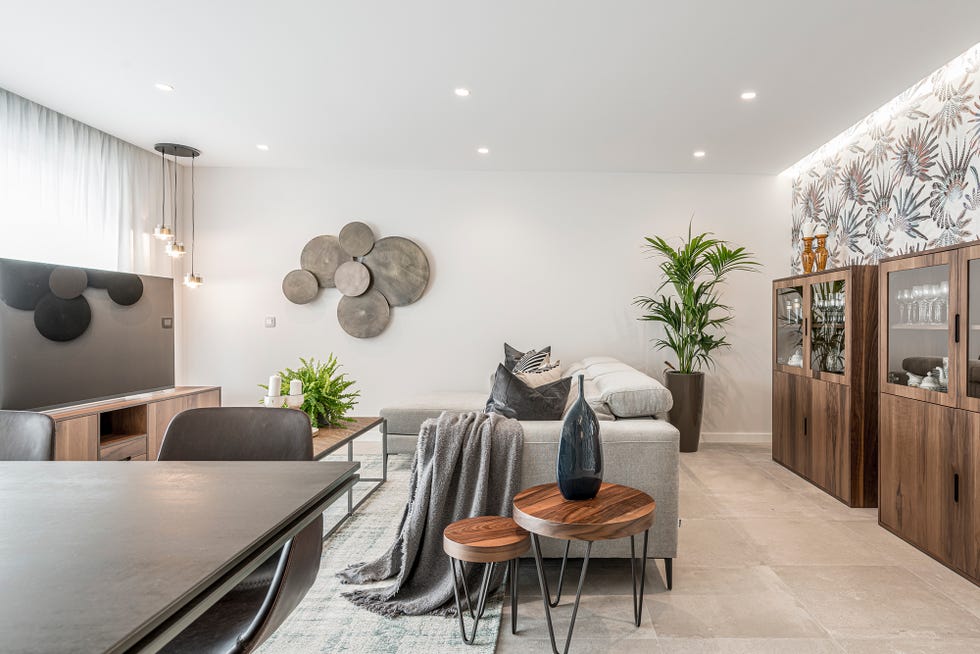 salón abierto decorado en grises con muebles de madera y un mural floral