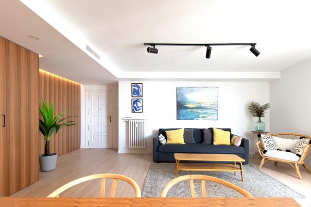 salón abierto con pared de madera de eucalipto y paredes pintadas en blanco