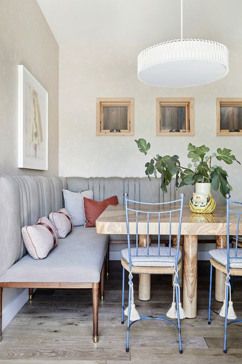 comedor de diseño ecléctica con mesa de madera, banco tapizado y sillas de forja azul
