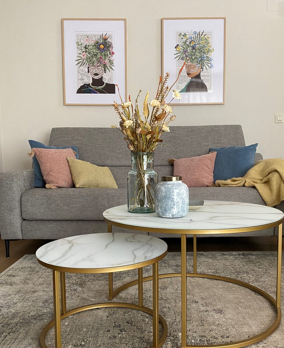 salón con sofá gris y mesa de centro dorada con sobre de mármol